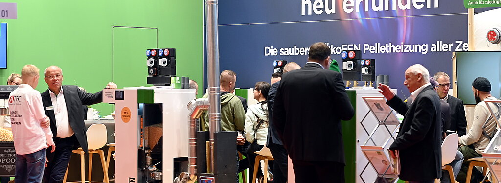 Der Messestand zeigt Pelletheizungen von ÖkoFEN, umgeben von Fachleuten und Besuchern, die sich über nachhaltige Heizsysteme informieren.