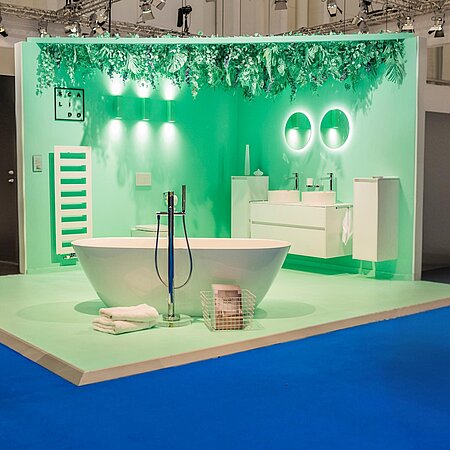 Ausstellungsbadezimmer mit freistehender Badewanne. Wand und Boden sind in hellgrün gestaltet.