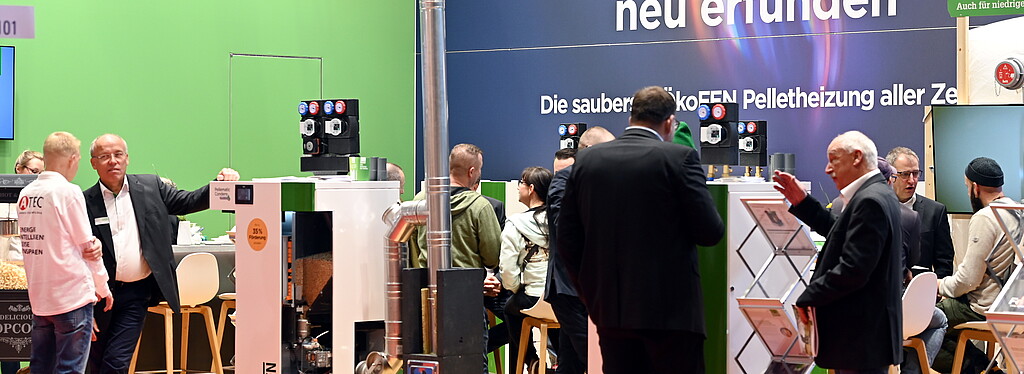 Der Messestand zeigt Pelletheizungen von ÖkoFEN, umgeben von Fachleuten und Besuchern, die sich über nachhaltige Heizsysteme informieren.